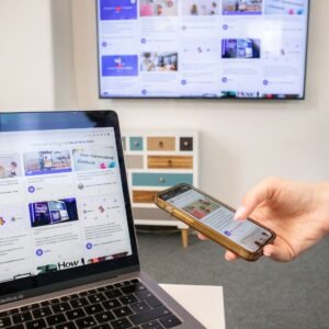 a person holding a cell phone in front of a laptop